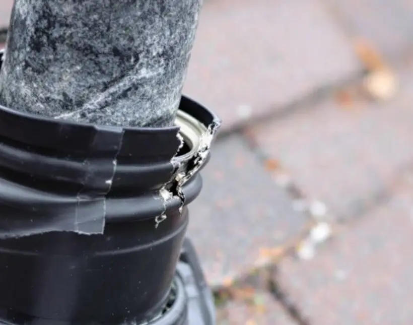 Cracked rubber pipe boot around a plumbing vent on a shingle roof