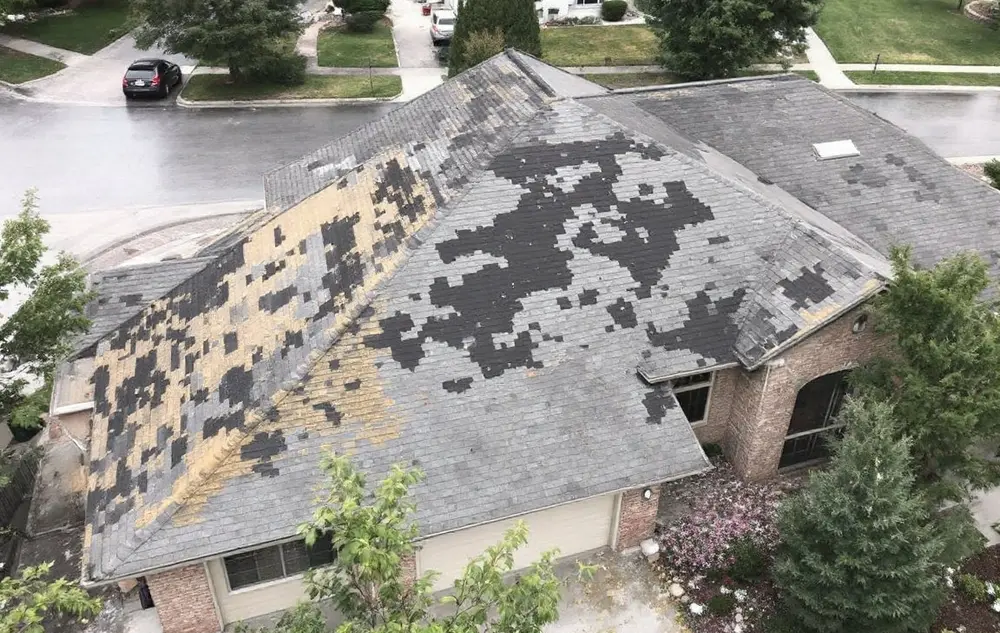 Worn-out shingle roof on a 1990s two-story home, tabs missing and faded