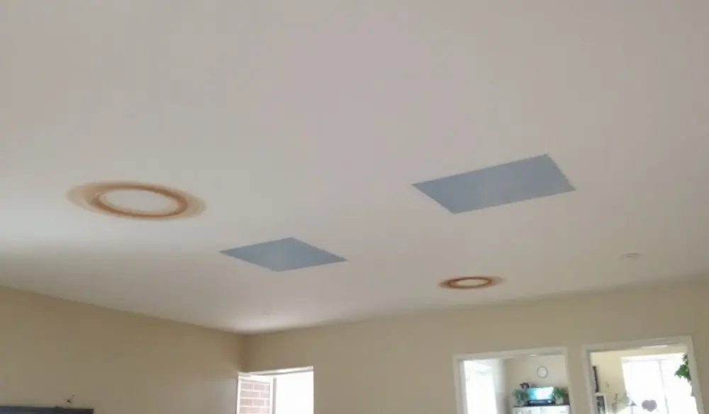 Ceiling with repeat water-stain rings and patched drywall from recurring roof leaks