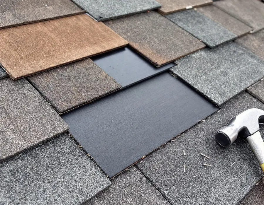 A new shingle set into the gap where damaged ones were pulled, hammer and nails beside