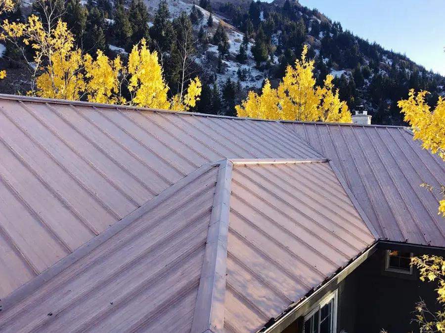 Mellowed copper-brown standing seam roof among autumn aspens